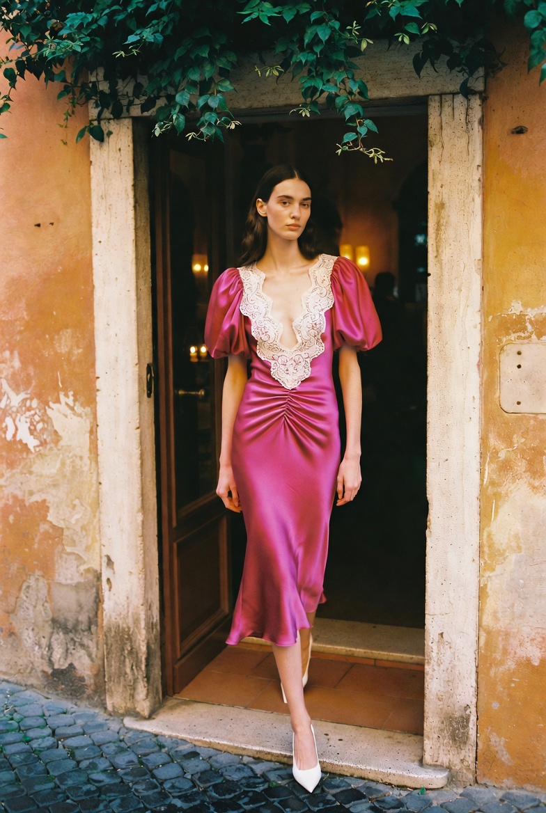 Think Pink — a tall slender model entering a chic Roman trattoria at golden hour in a romantic pink floral off-shoulder midi dress, the ESVRA Fashion edit on 2026's pink trend